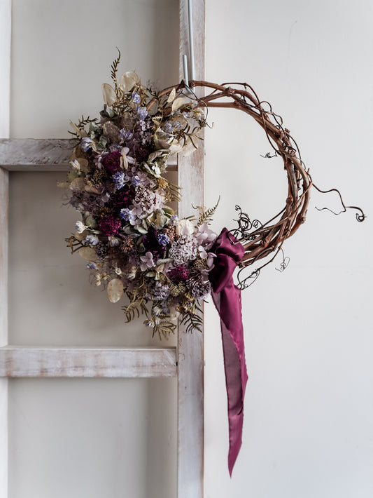 Dried flower wreath in soft blue violet tones on a grapevine base - Mystique Distant View.