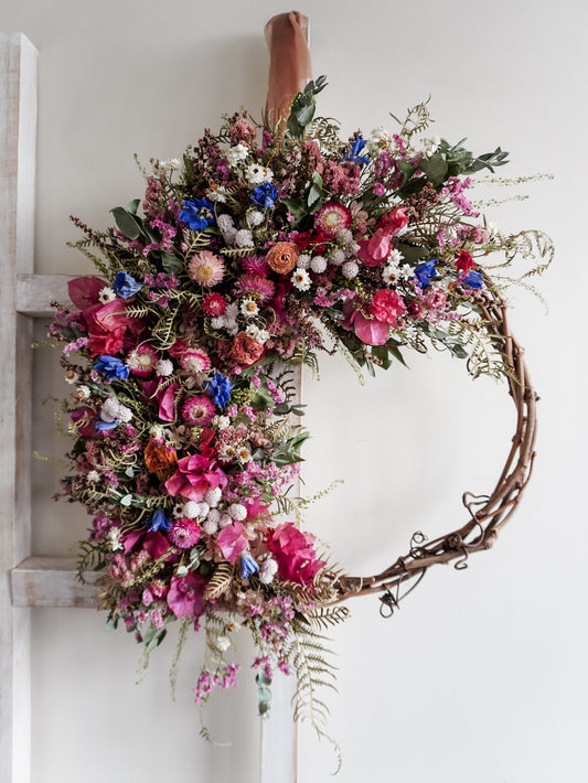 Dried flower wreath in bright, colourful tones with spring florals on a grapevine base – close full view.
