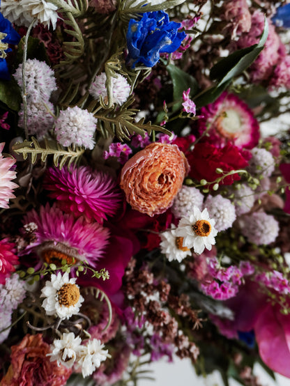 Dried flower wreath in bright, colourful tones with spring florals on a grapevine base – zoomed in view.