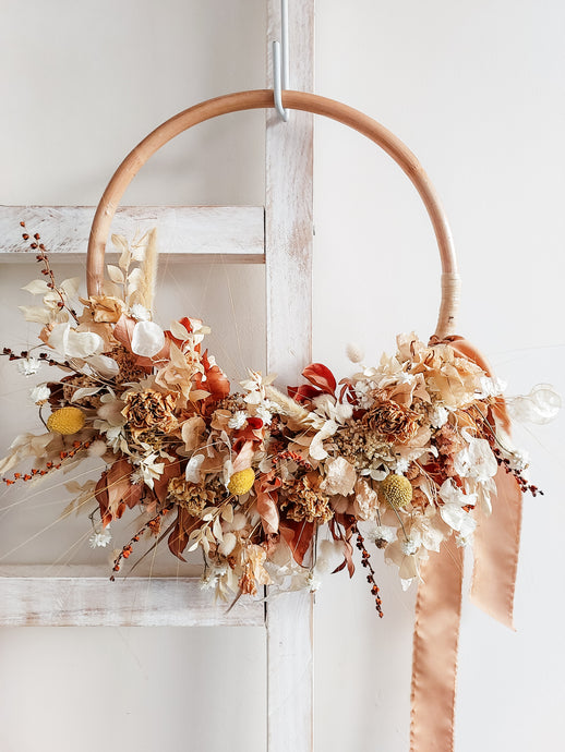 Dried flower wreath in warm tones on a rattan hoop base – close full view.