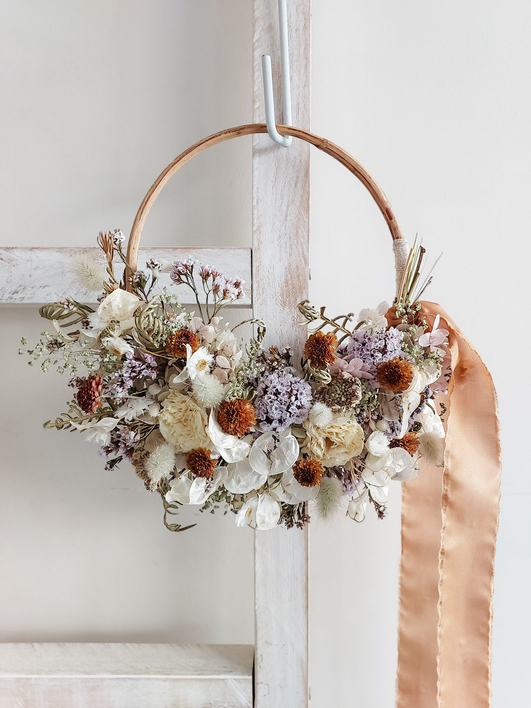 Dried flower wreath in lilac tones on a rattan hoop base – close full view.