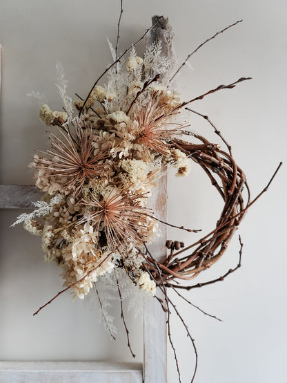 Dried flower wreath in nude neutral tones spray design on a grapevine base – close full view.