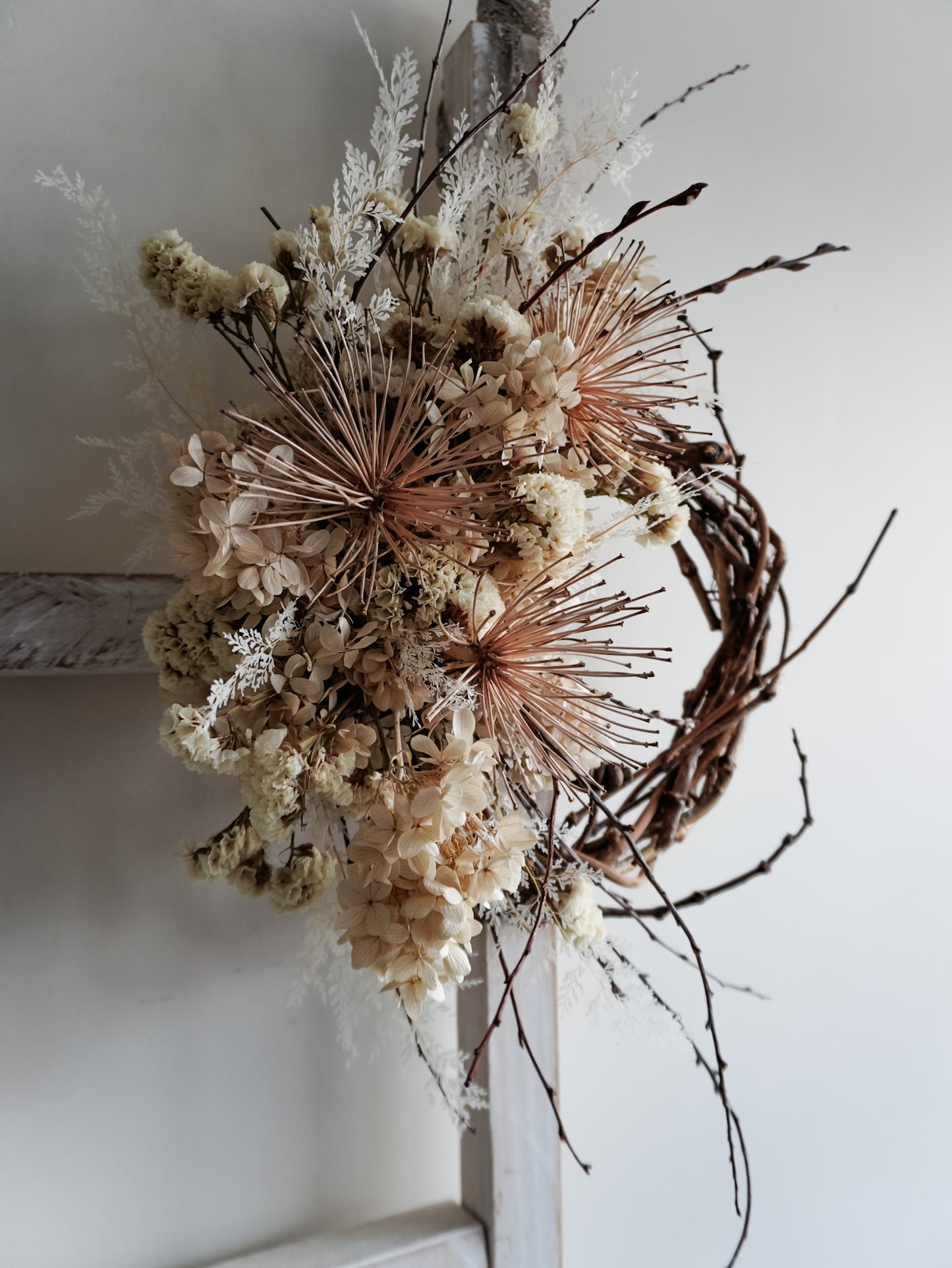 Dried flower wreath in nude neutral tones spray design on a grapevine base – side full view.