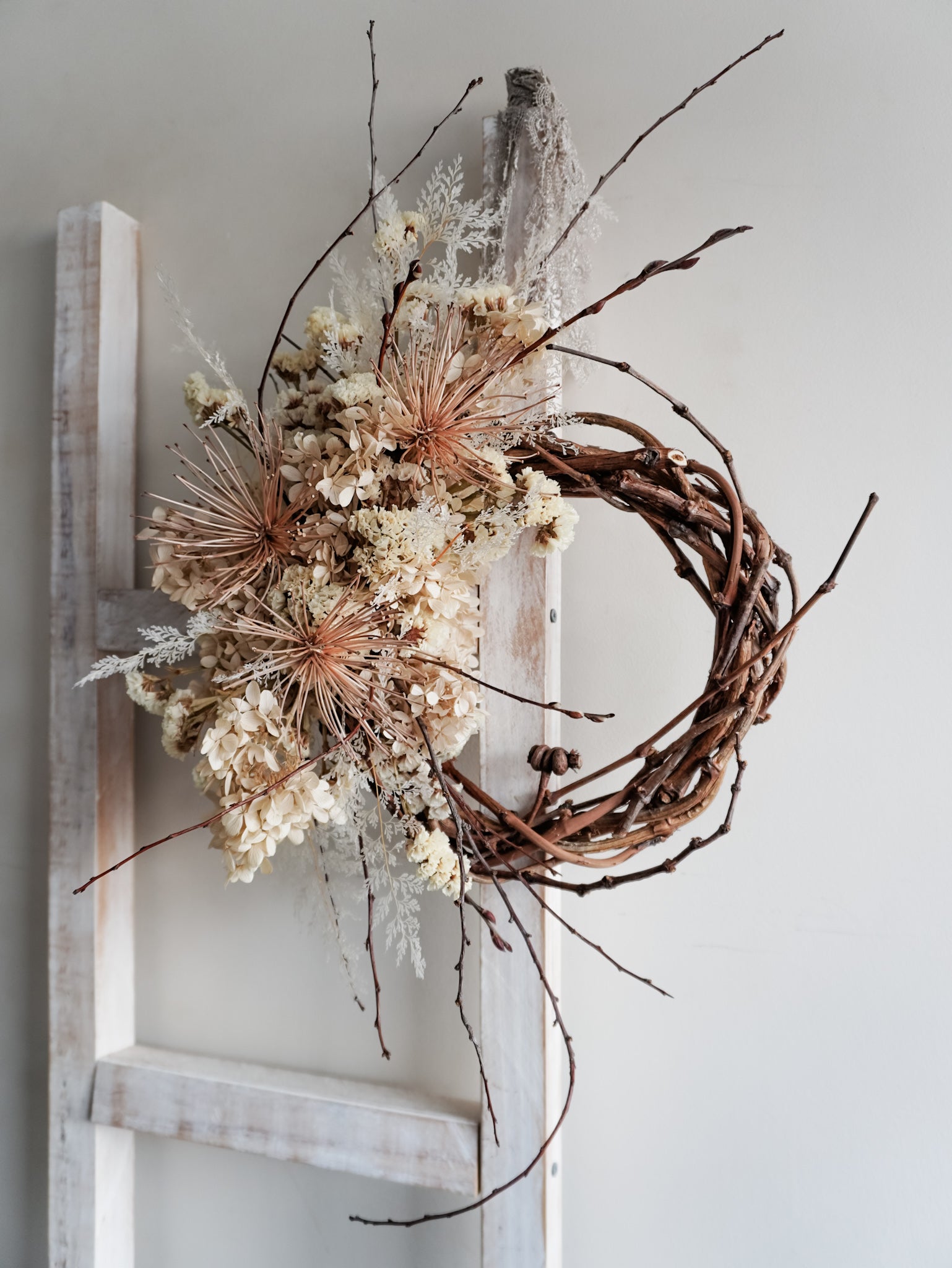 Dried flower wreath in nude neutral tones spray design on a grapevine base - side view.