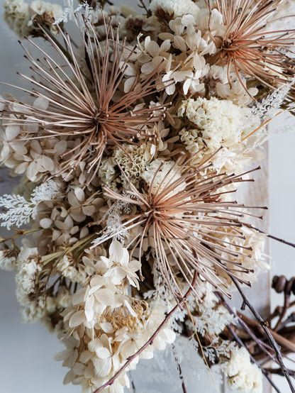 Dried flower wreath in nude neutral tones spray design on a grapevine base – close up view of agapanthus.