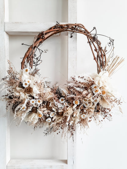Dried flower wreath in rustic neutrals on a grapevine base.