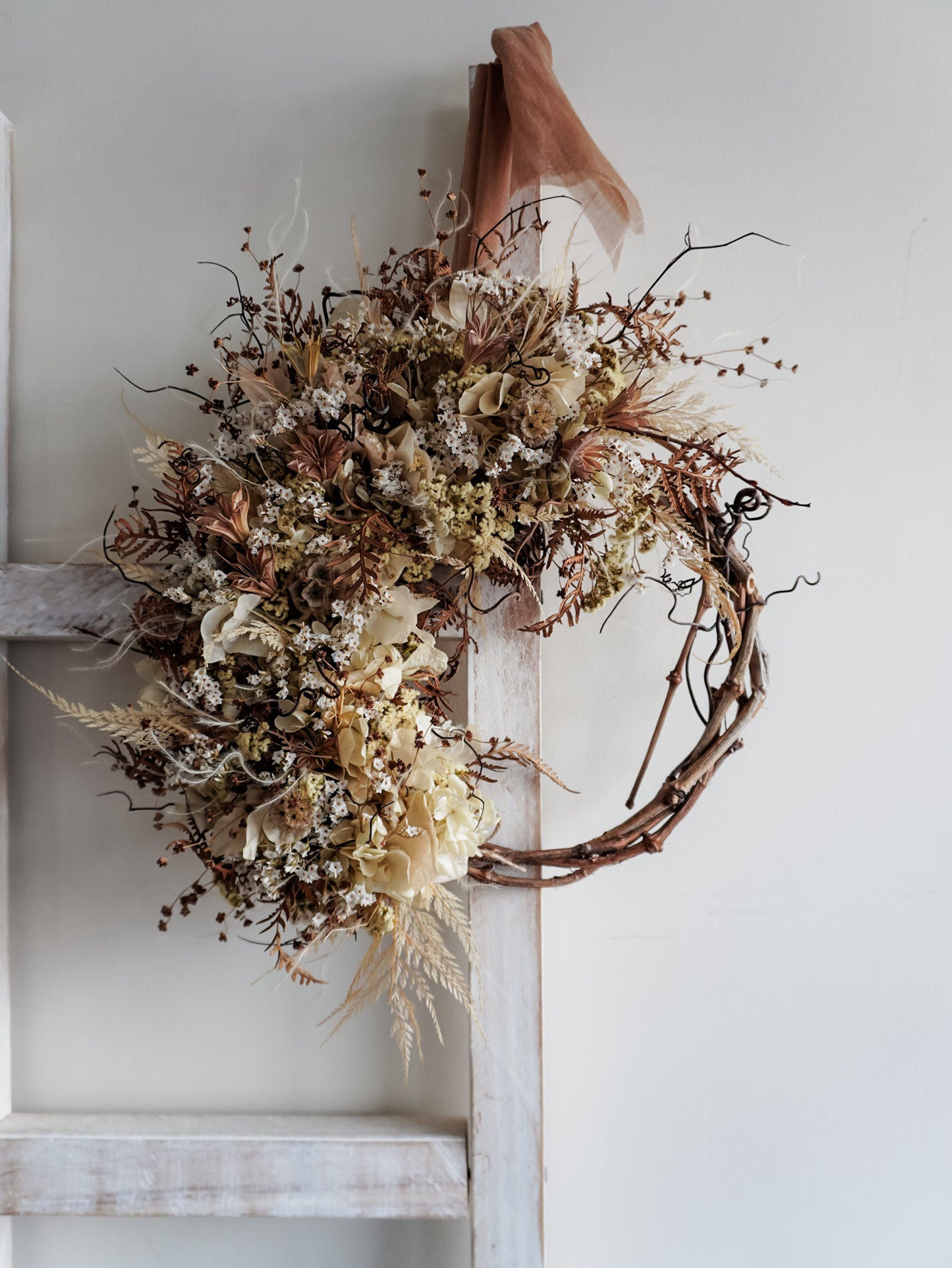 Dried flower wreath in neutral tones boho style on a grapevine base – distant full view.