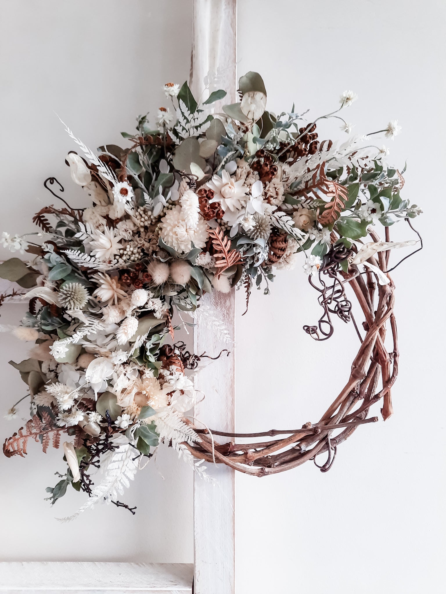 Dried flower wreath in a natural, rustic style on a grapevine base.