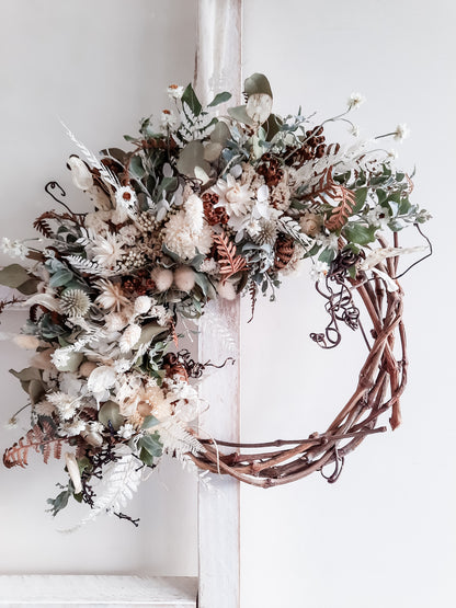 Dried flower wreath in a natural, rustic style on a grapevine base.
